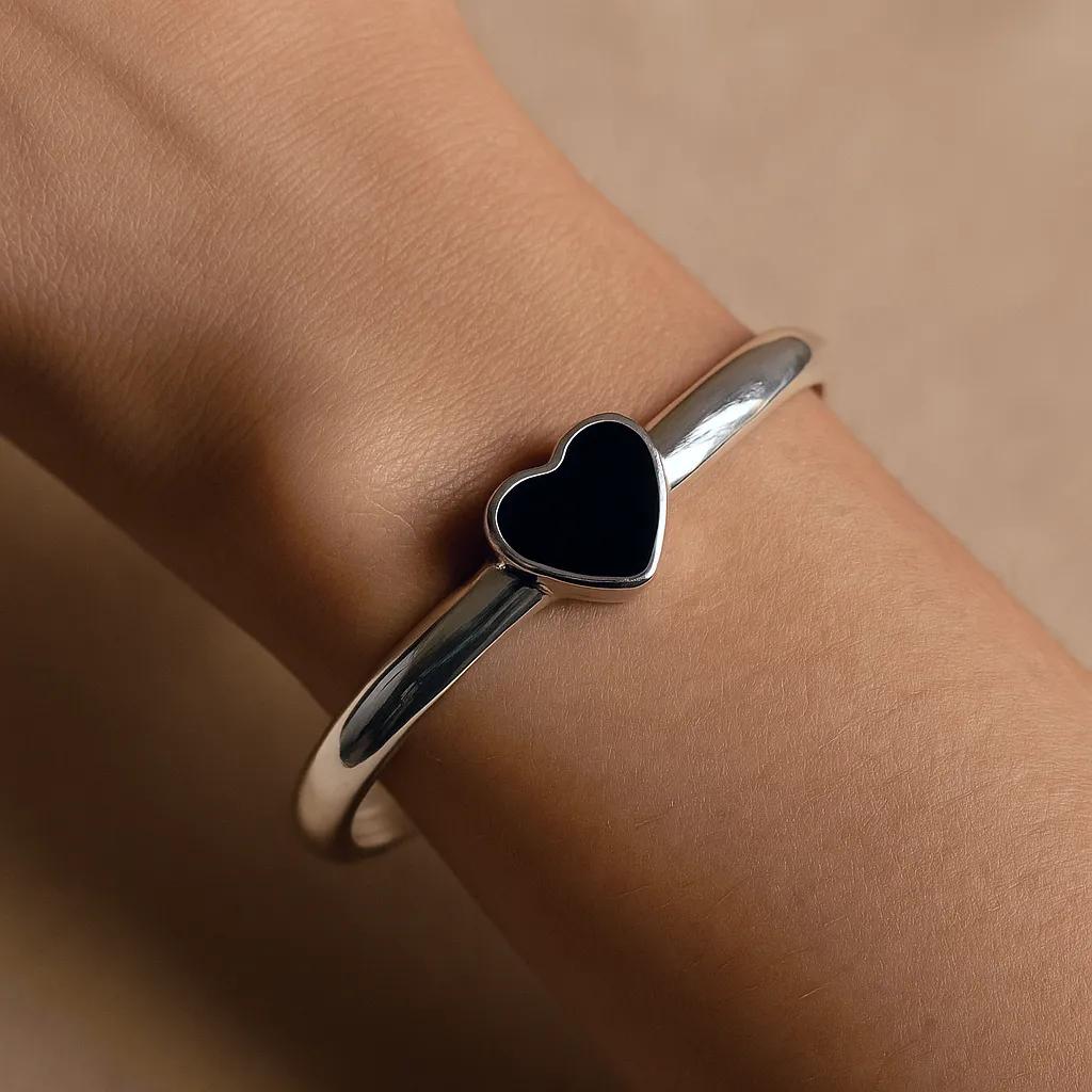Close-up of sterling silver bracelet with black heart stone on white background