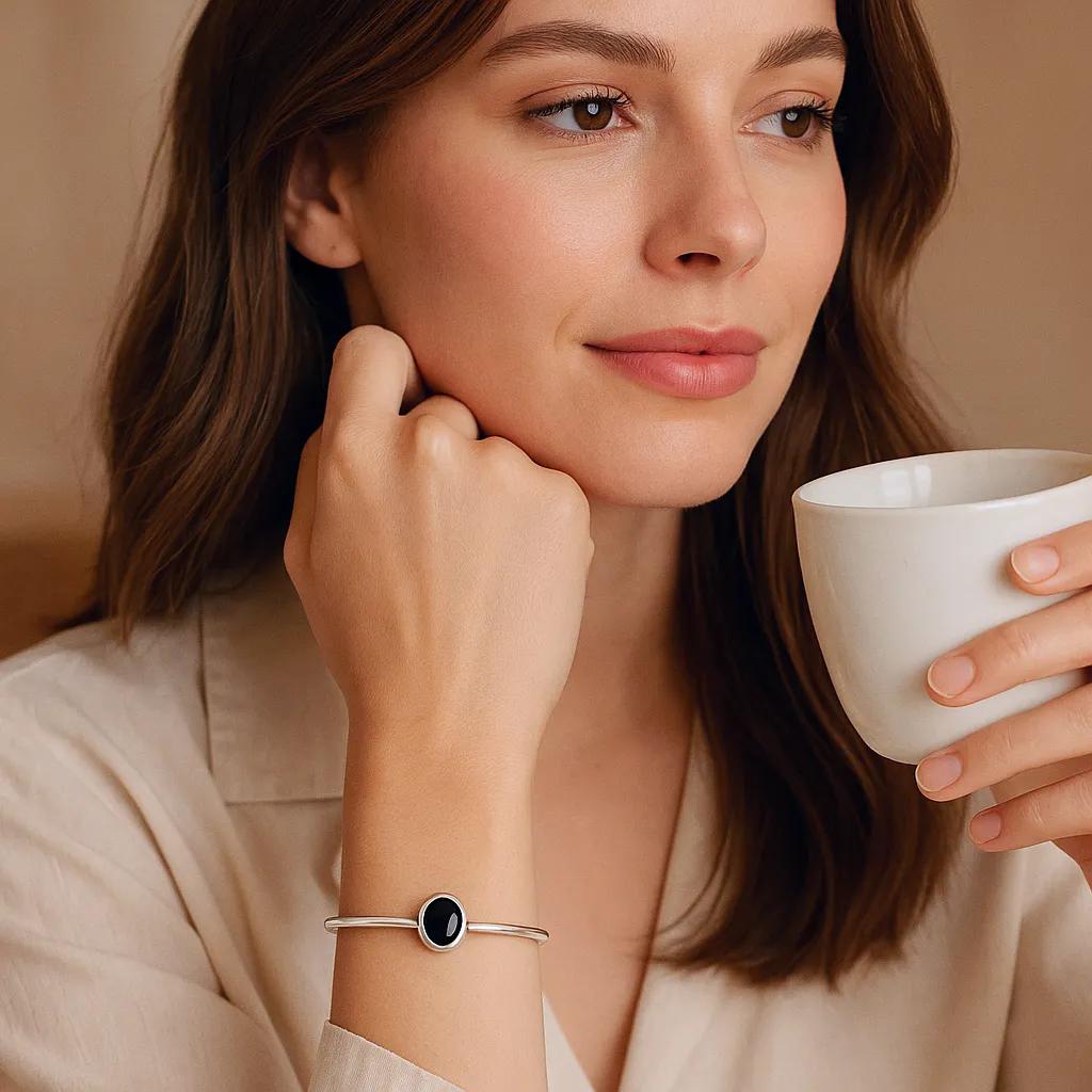 Minimalist silver bracelet with black oval stone on woman's wrist