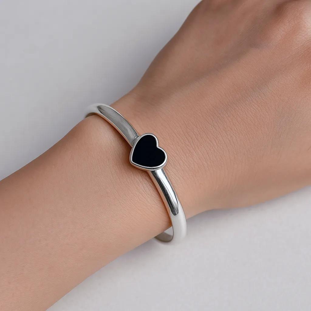 Model wearing minimalist silver bracelet with black stone centerpiece