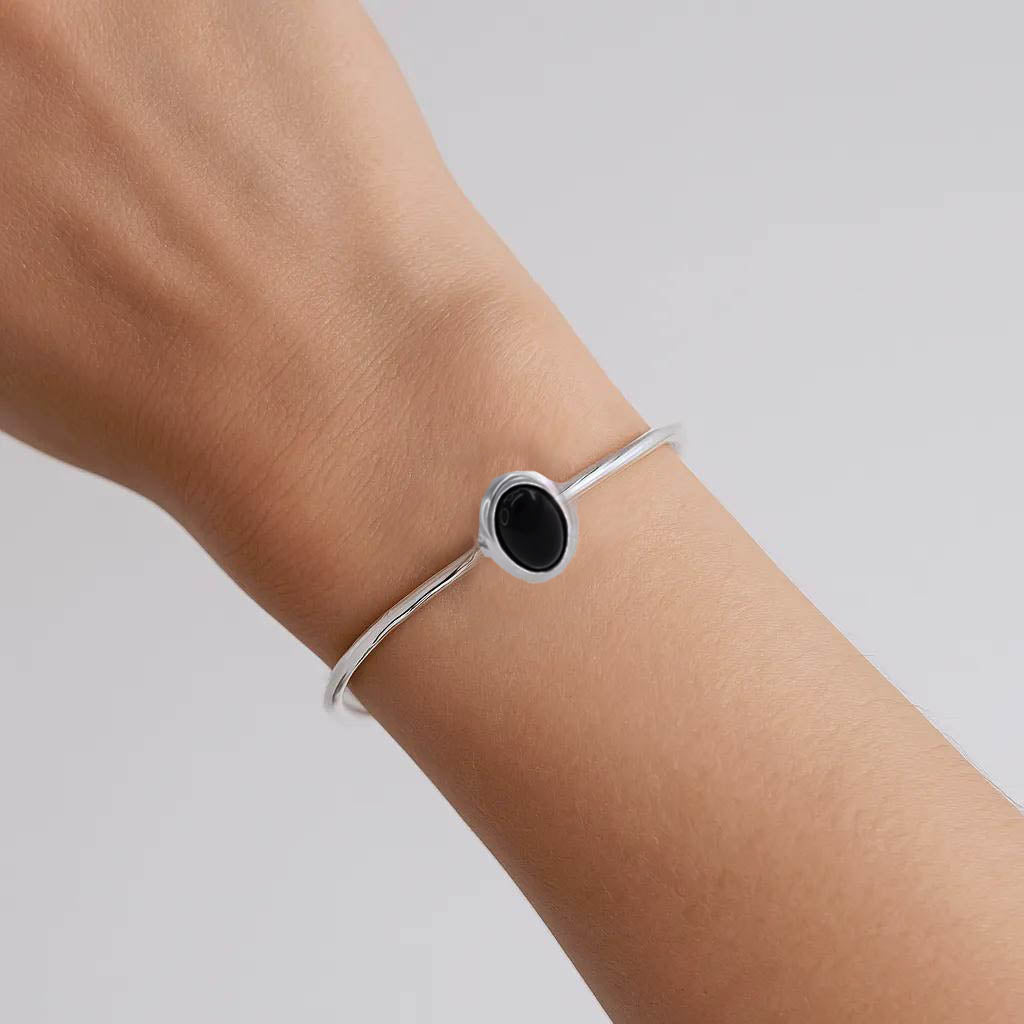 Minimalist silver bracelet with black oval stone on woman's wrist