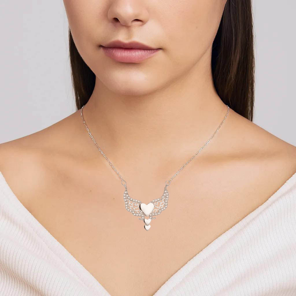 Close-up of intricate heart and wing detail, silver finish.