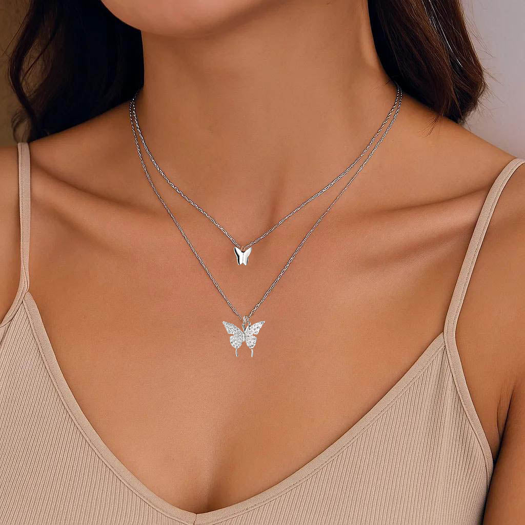 Close-up of layered silver necklace with butterfly charm.