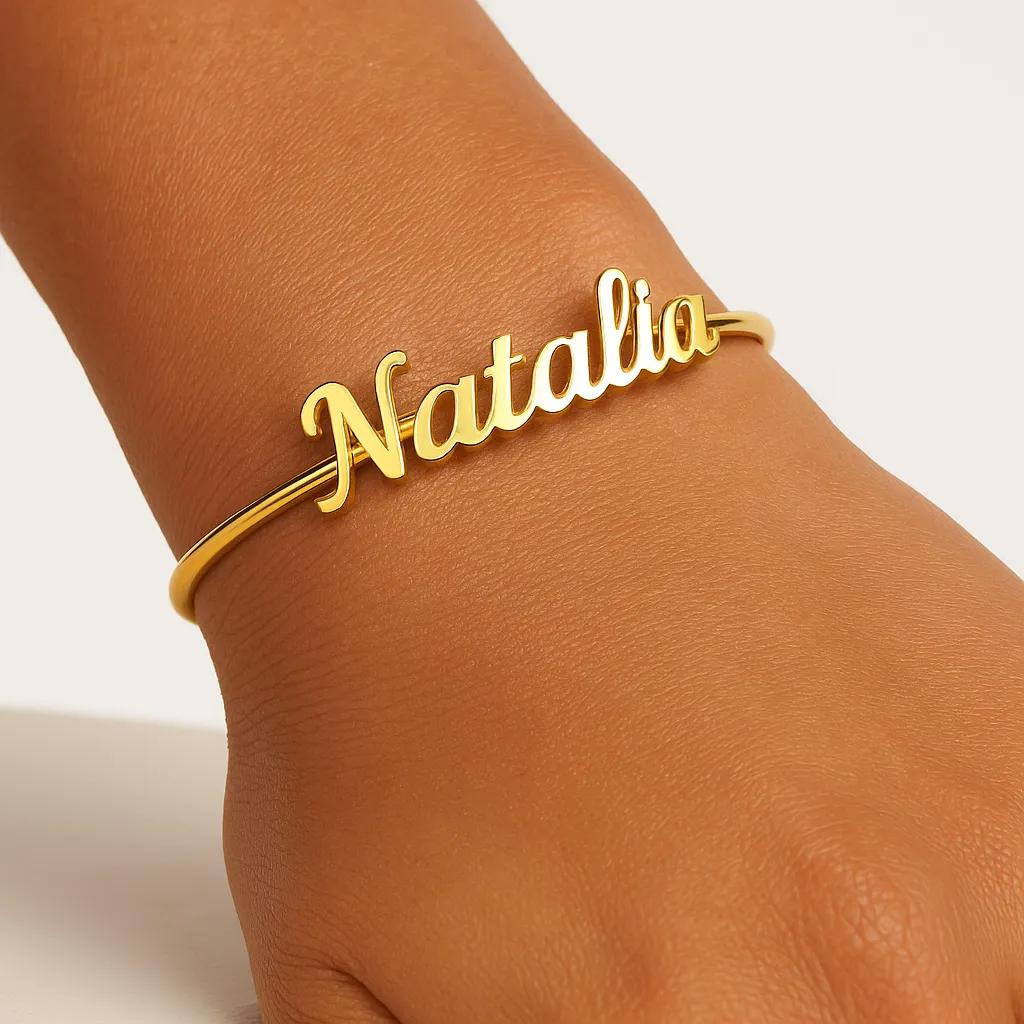 Gold bracelet with 'Natalia' on a wrist against a neutral background