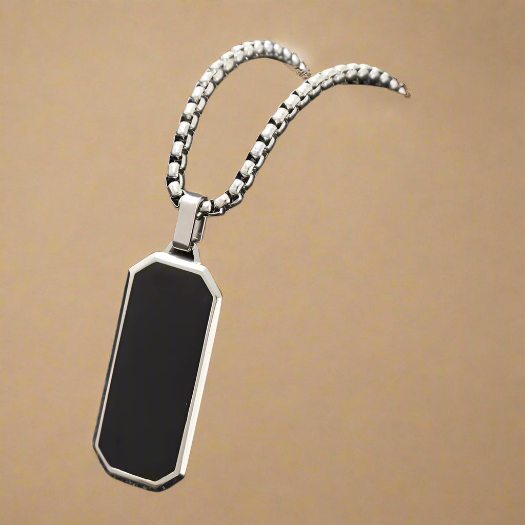 Geometric gold-edged black enamel pendant for men – styled on stone background