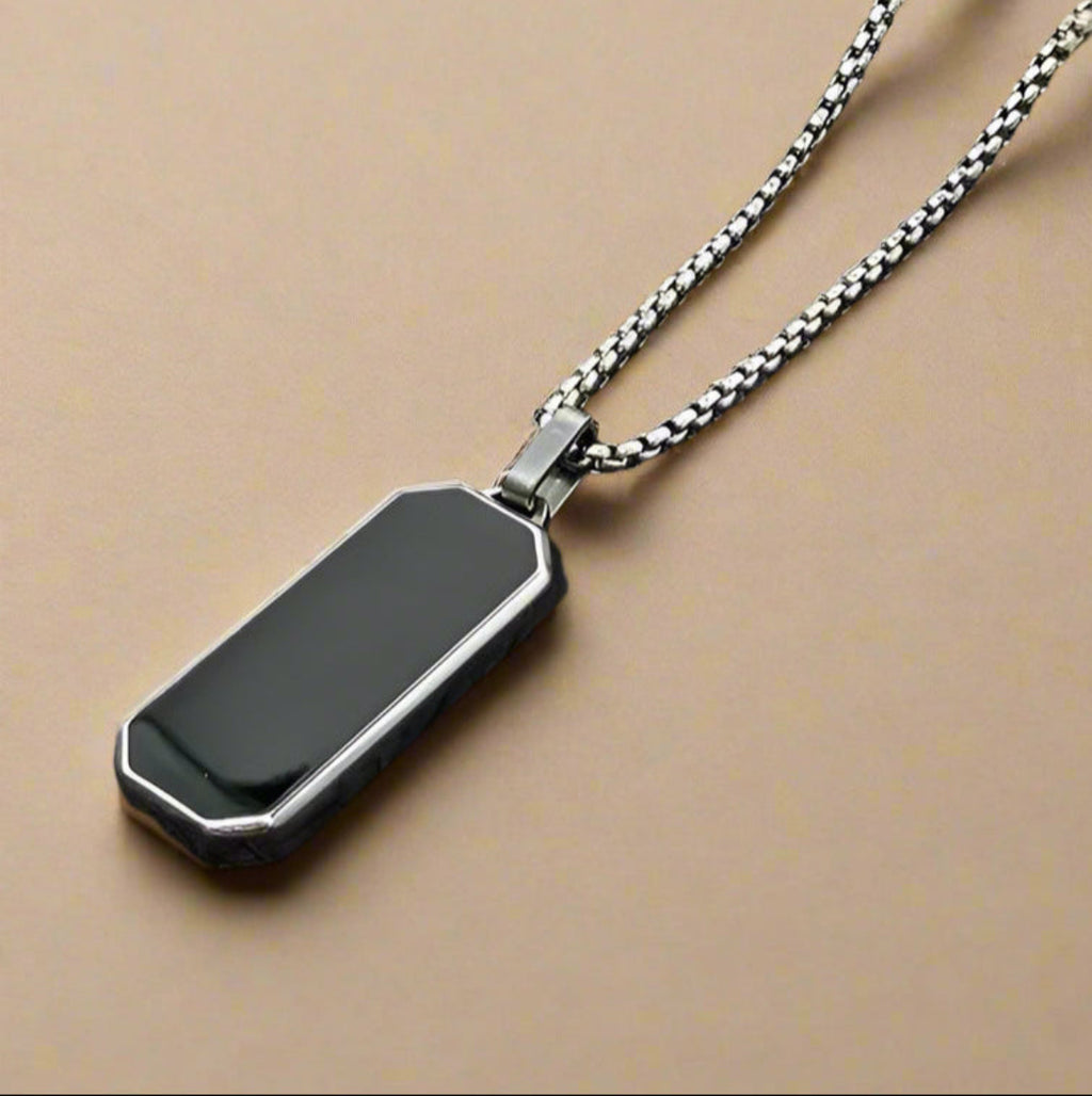 Geometric gold-edged black enamel pendant for men – styled on stone background