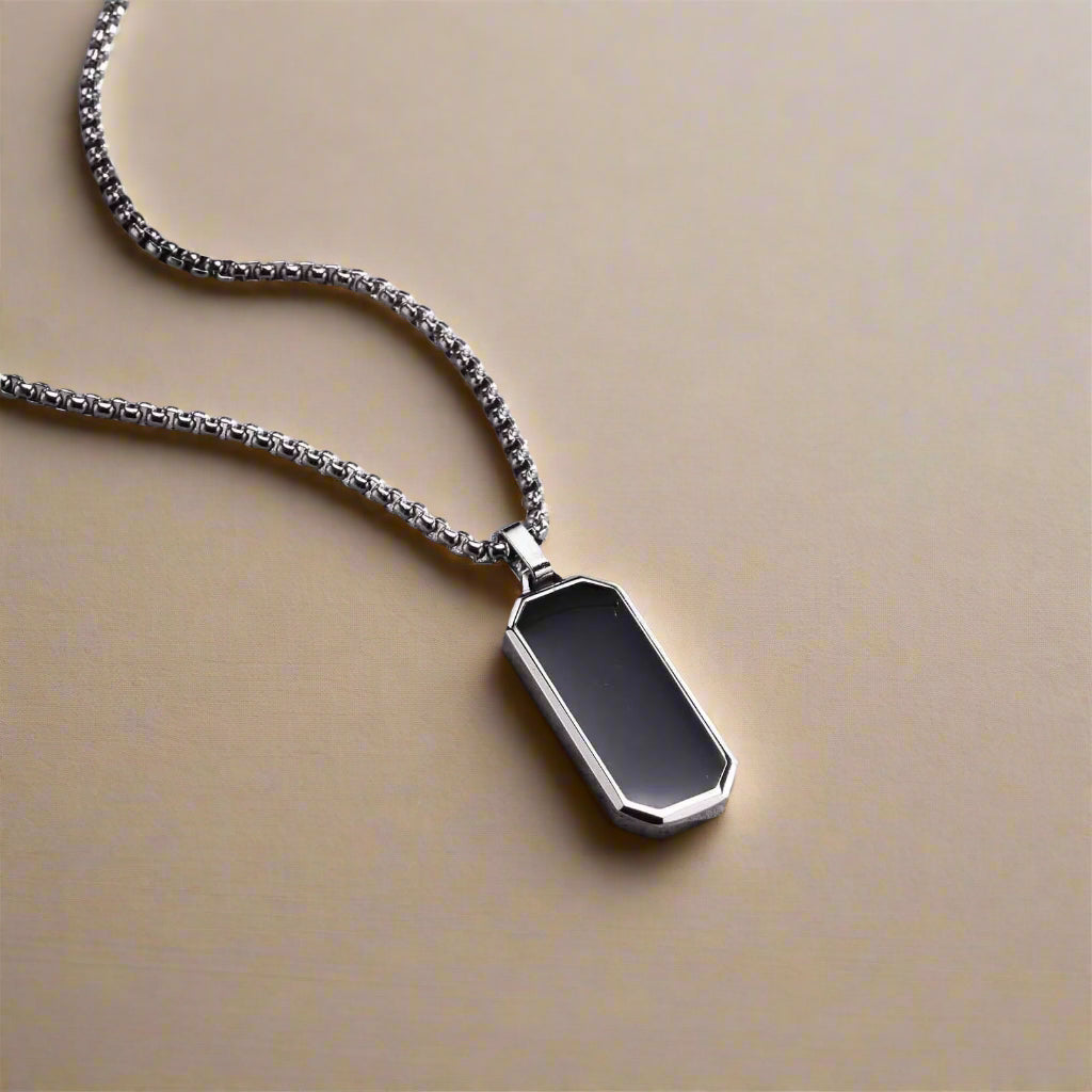 Geometric gold-edged black enamel pendant for men – styled on stone background