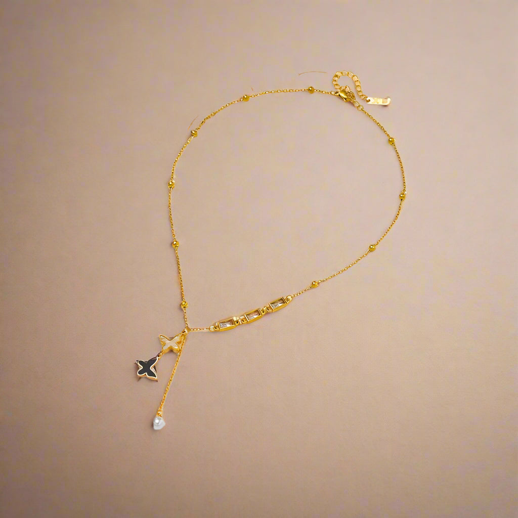 Double butterfly pendant necklace in gold, displayed on a beige jewelry box