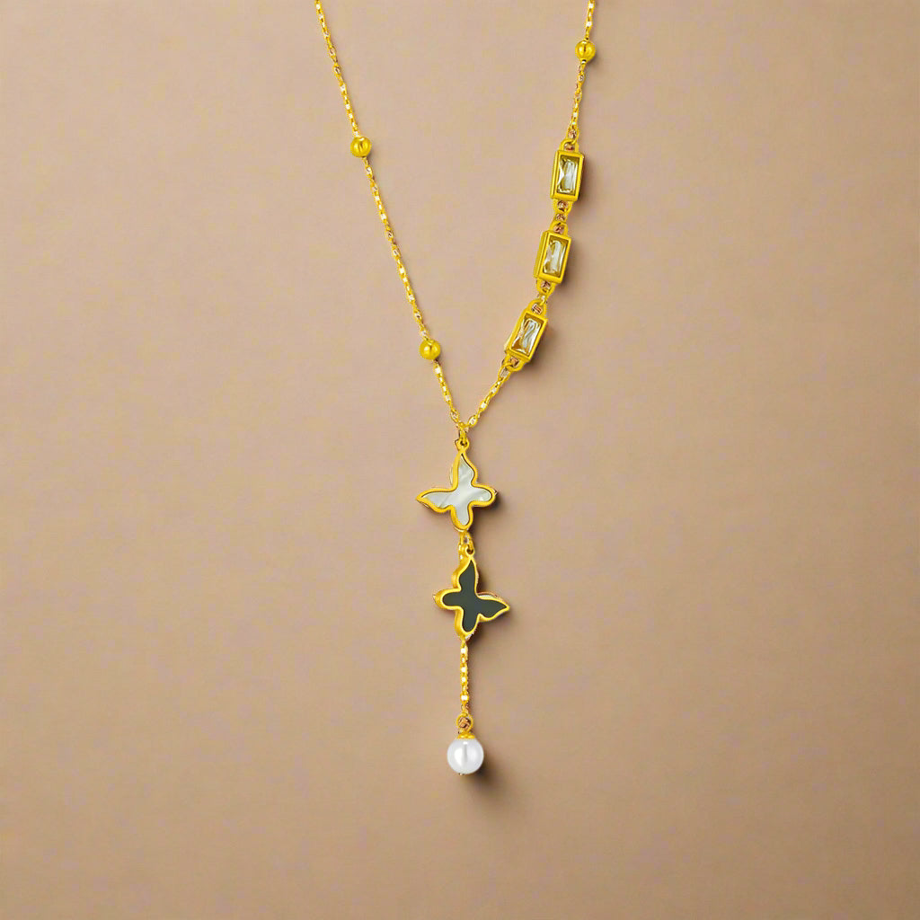 Double butterfly pendant necklace in gold, displayed on a beige jewelry 