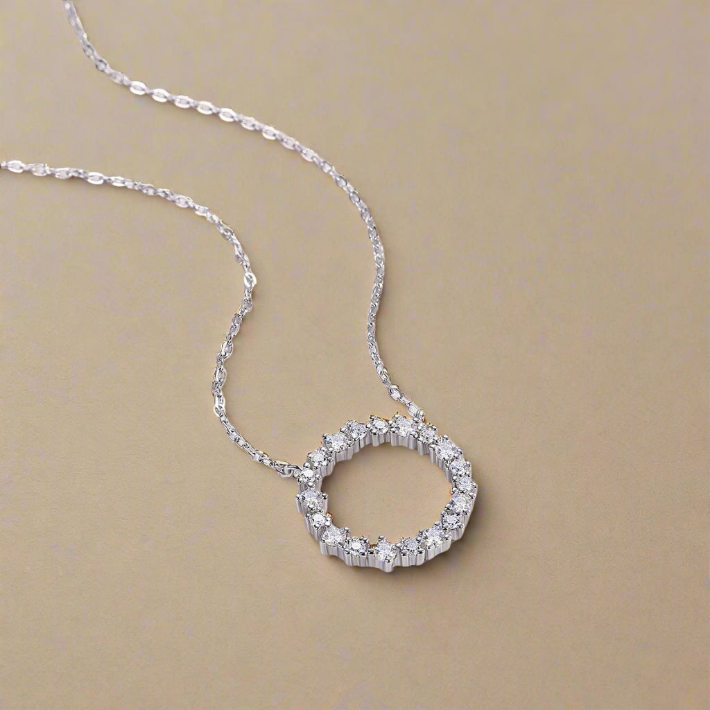 Silver necklace with a circular pendant on a beige background