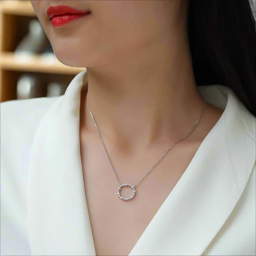 Necklace with a circular pendant worn by a person in a white outfit.