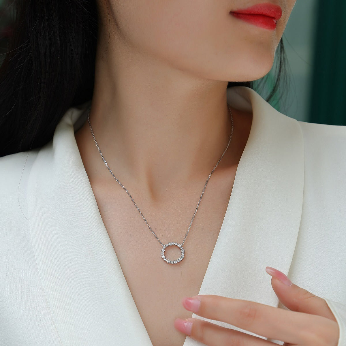 Close-up of a woman wearing a silver necklace with a circular pendant.