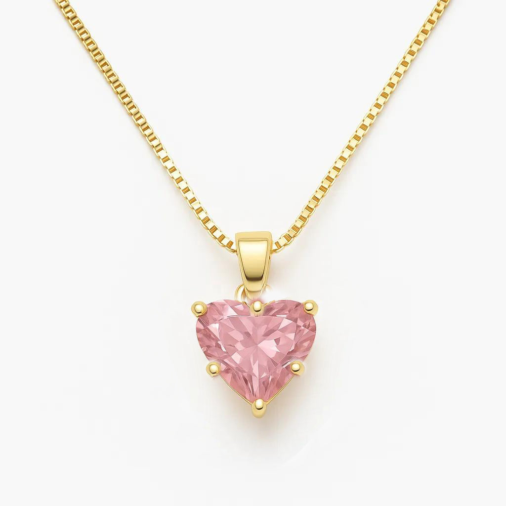 Gold necklace with a pink heart-shaped pendant on a white background