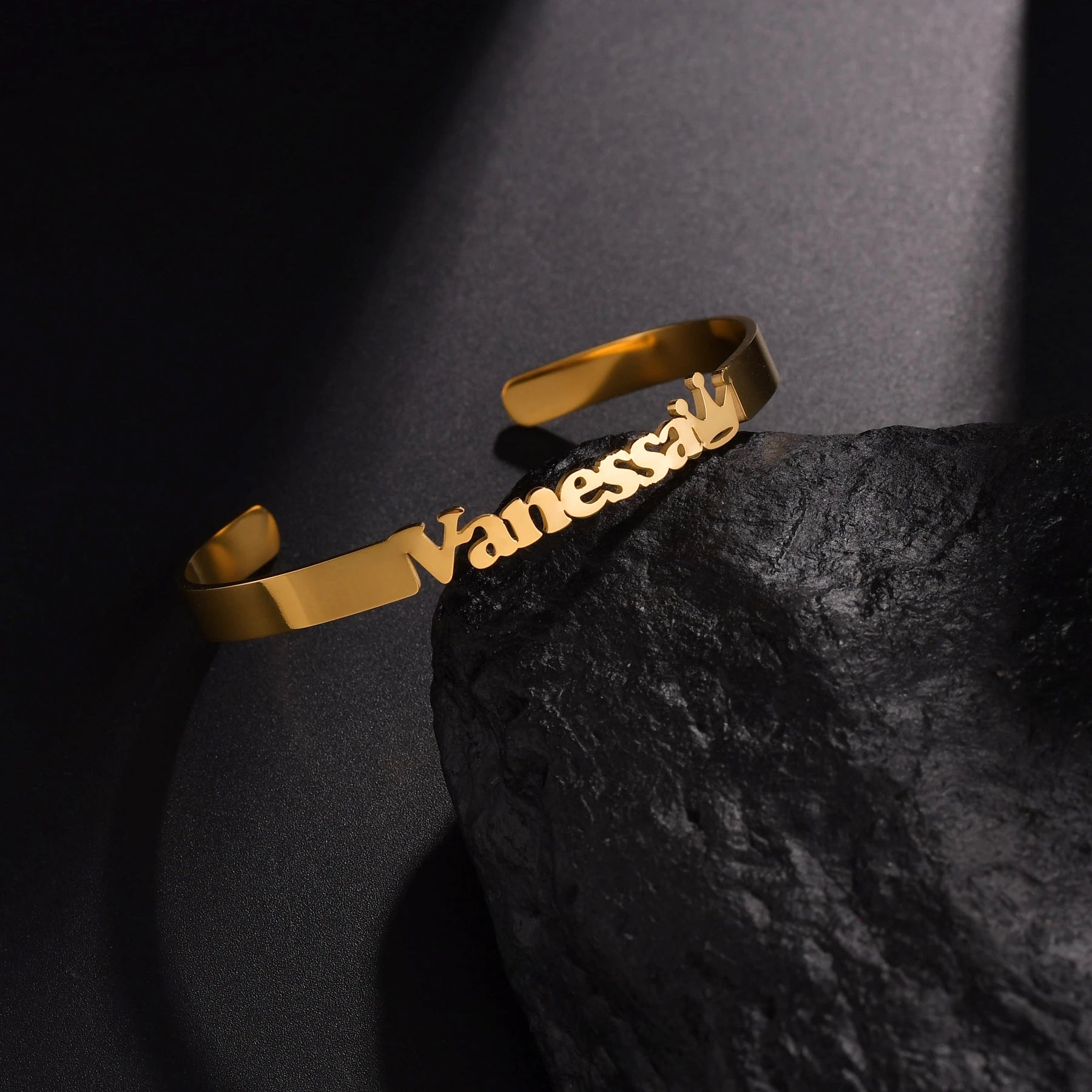 Gold bracelet with 'Vanessa' engraved on a dark stone surface