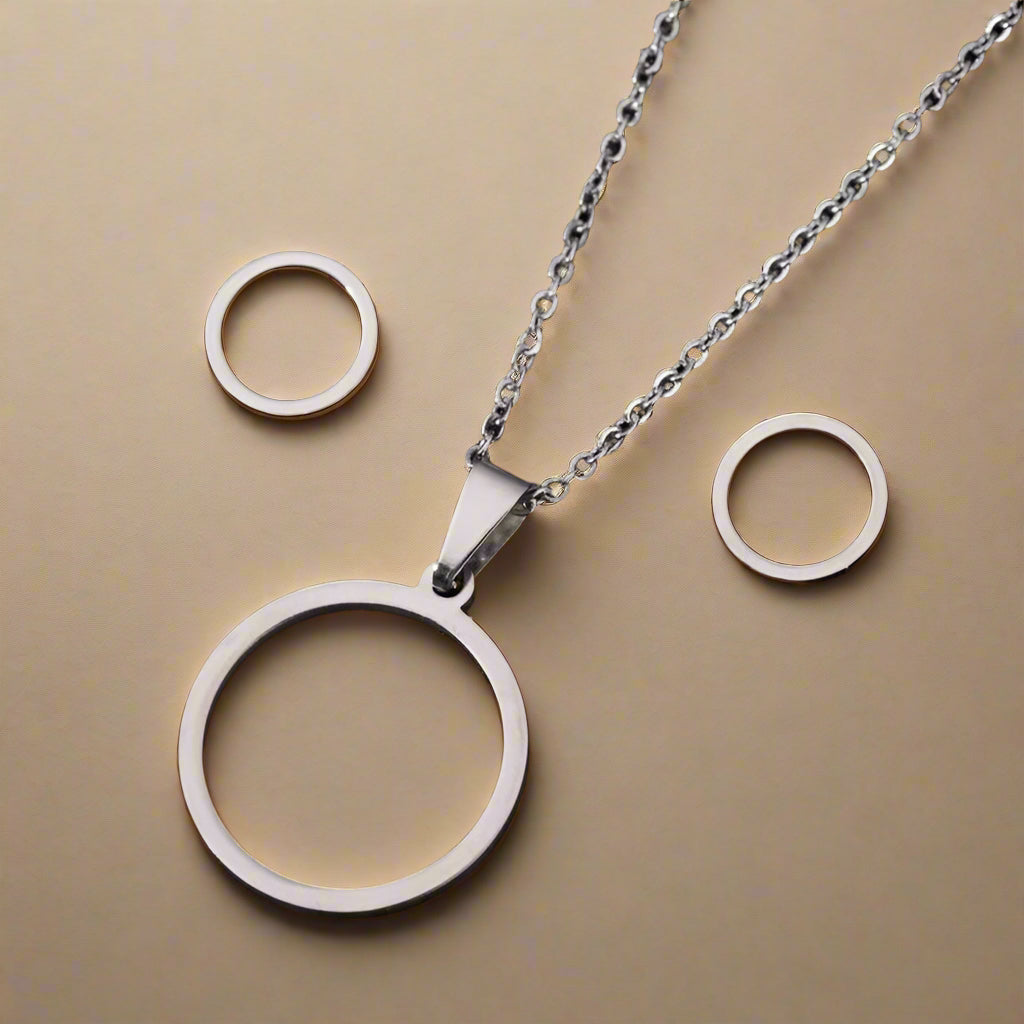 Silver minimalist circle pendant necklace and matching earrings on glitter fabric