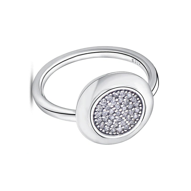 Silver ring with a round, diamond-studded center on a white background