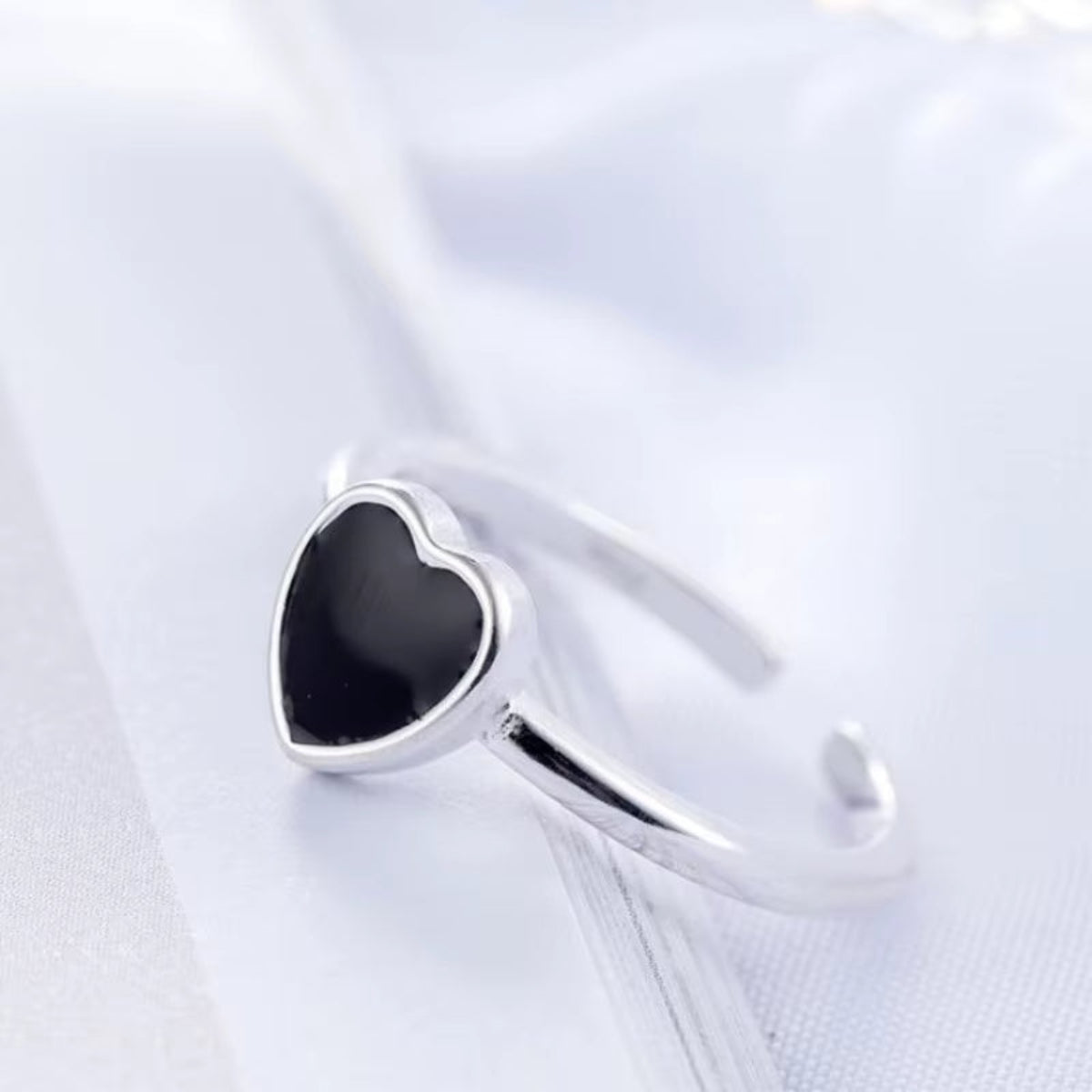 Silver ring with black square stone on soft beige background