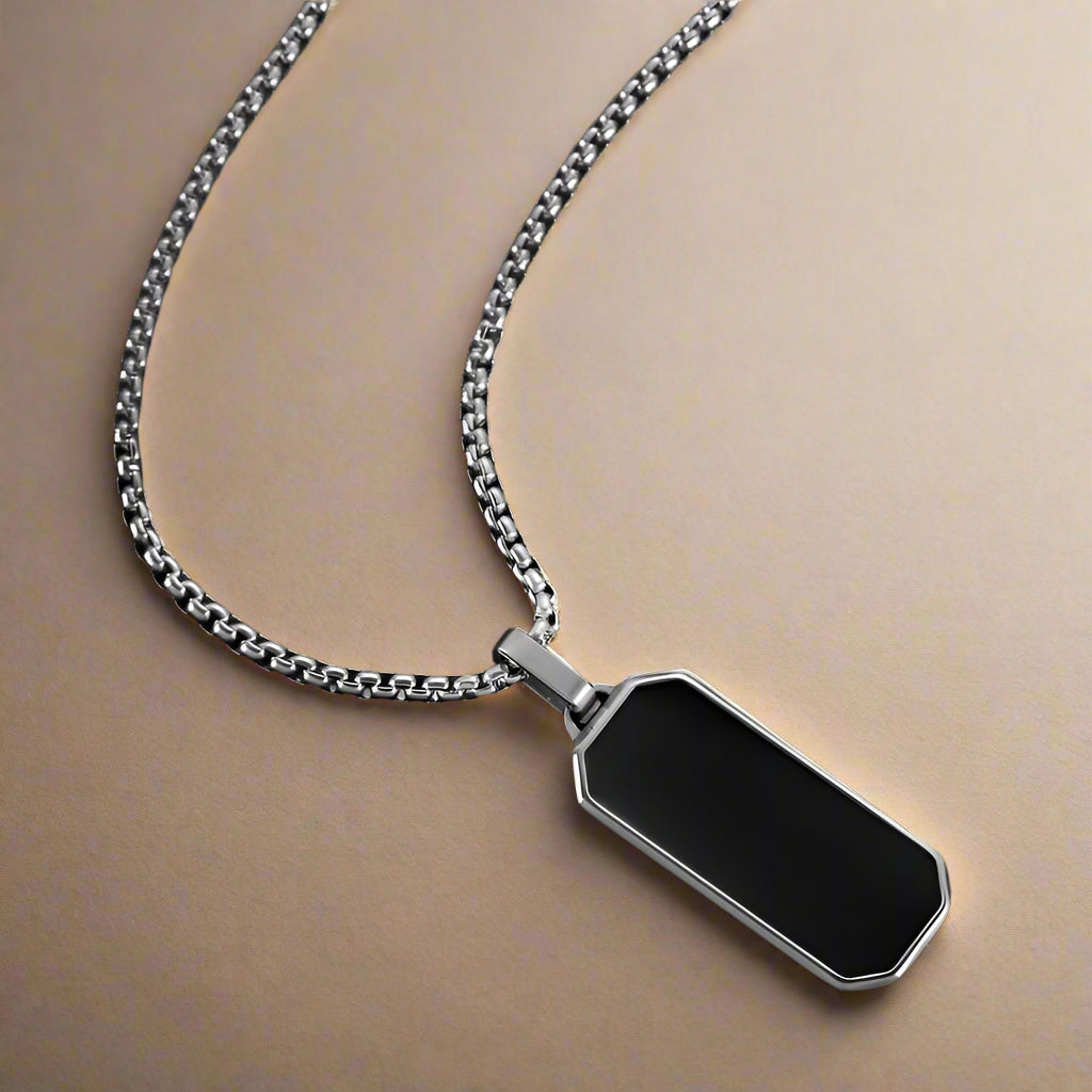 Close-up of men's silver stainless steel necklace with black enamel pendant