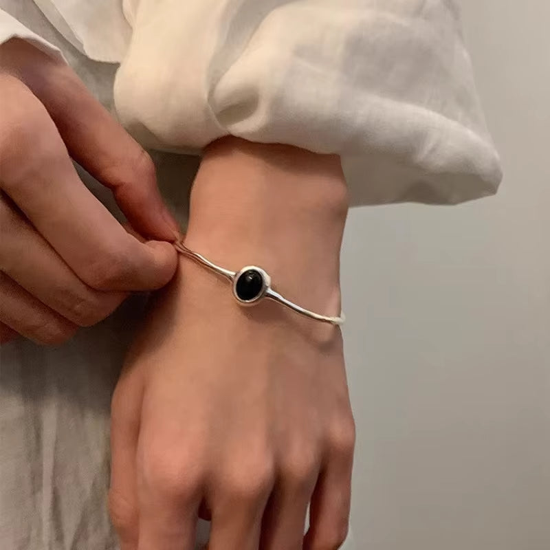 Minimalist silver bracelet with black oval stone on woman's wrist