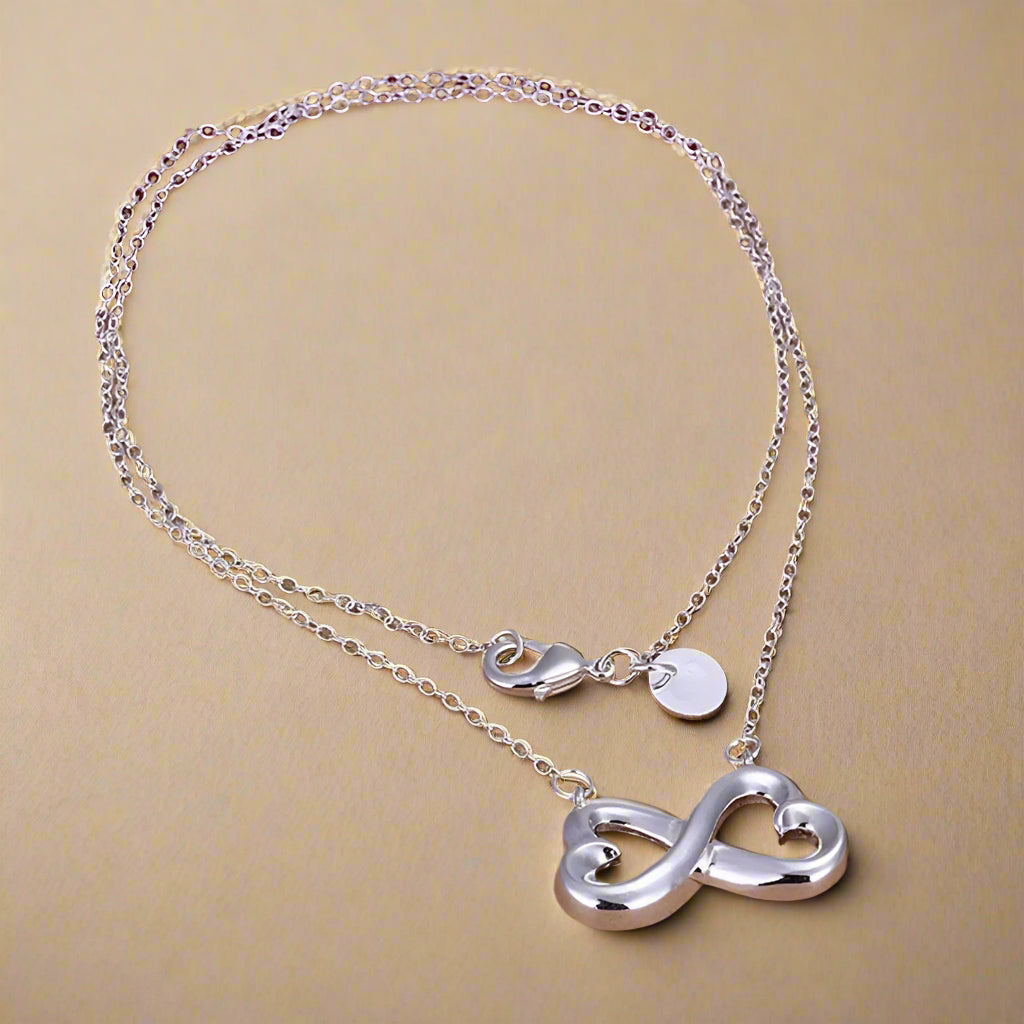  Elegant necklace with infinity and heart design in shimmering silver.