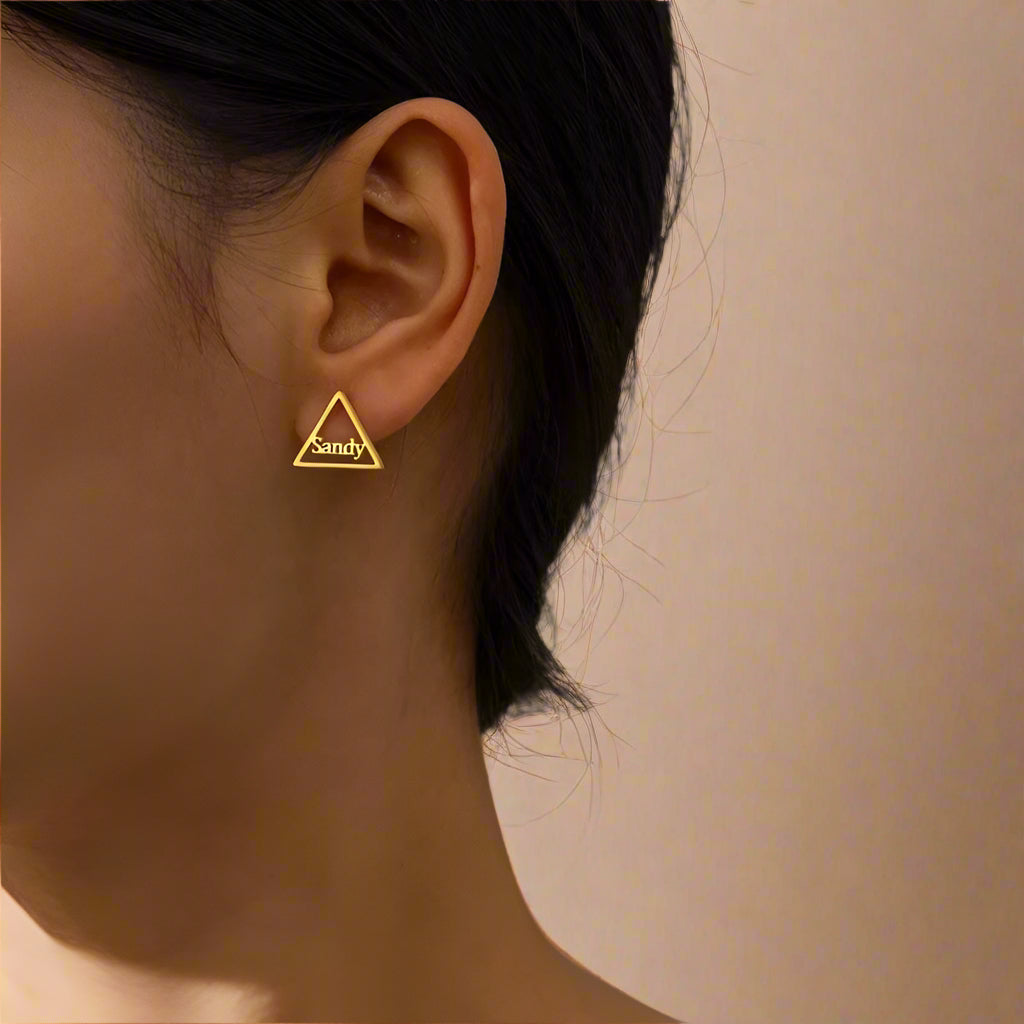 Close-up of personalized gold earrings shaped in a triangle.