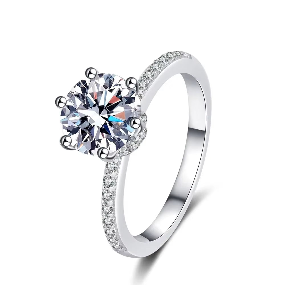 Close-up of moissanite engagement ring with crown-prong setting on sparkling teal background