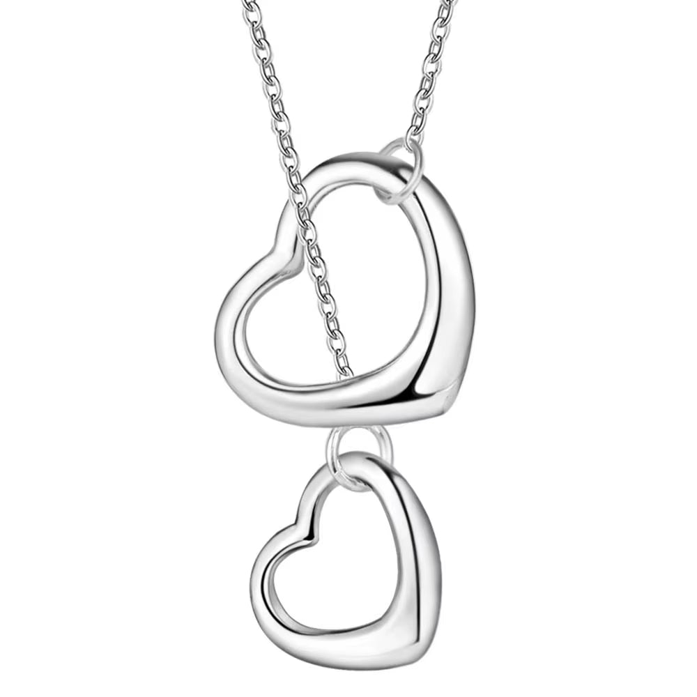 Silver necklace with two heart pendants on a fabric background.  