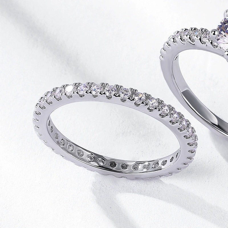 Elegant ring set with round center stone on a white background.