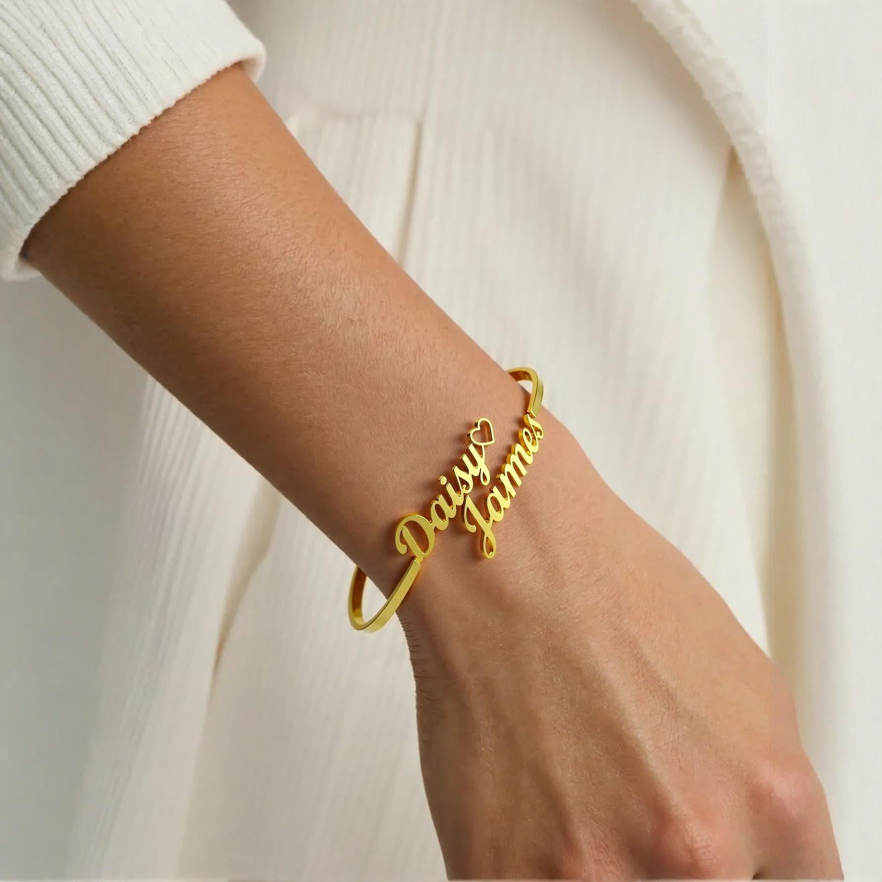 Gold bracelet with 'Daisy James' on a wrist against a neutral background