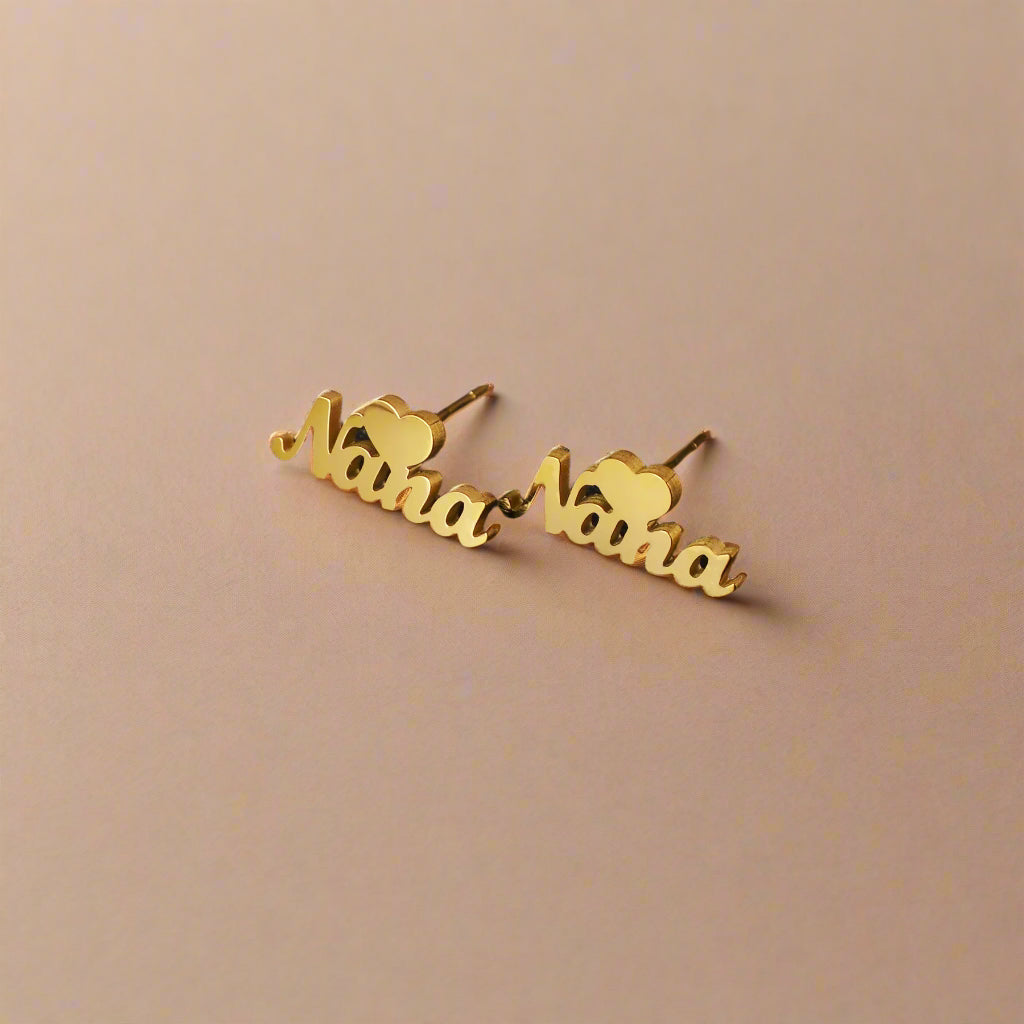 Elegant earrings spelling "Nana" on dark surface.