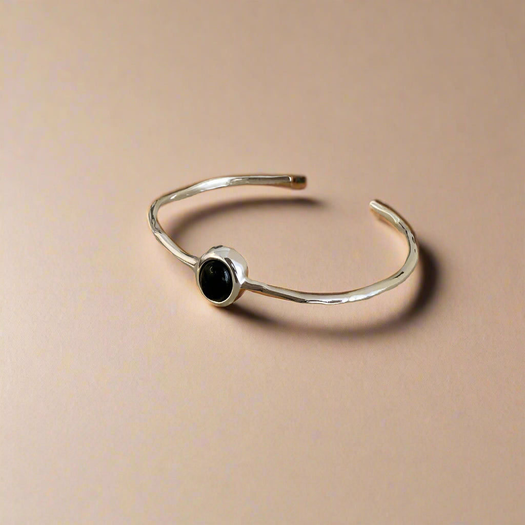 Minimalist silver bracelet with black oval stone on woman's wrist