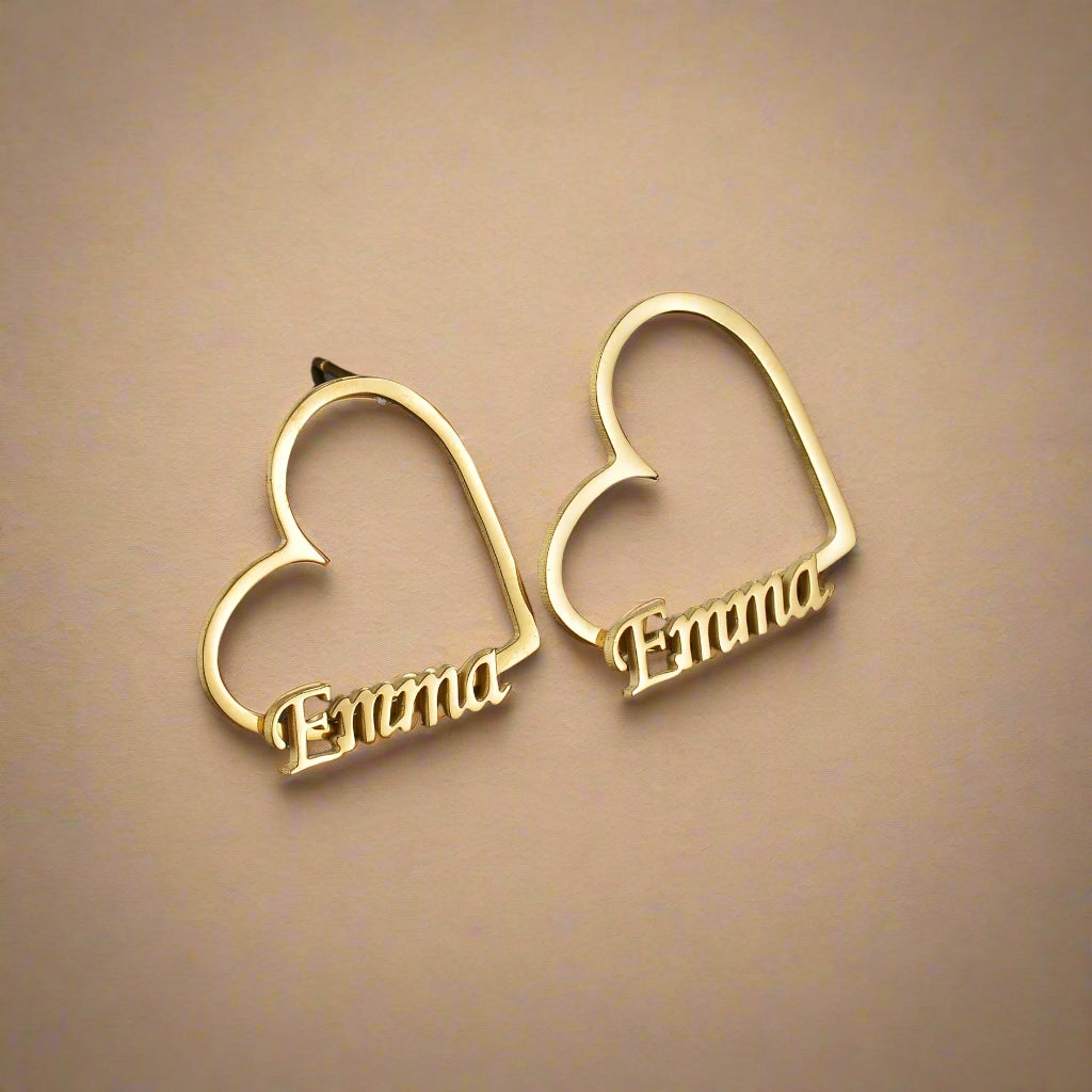 Gold earrings shaped like hearts with engraved names 