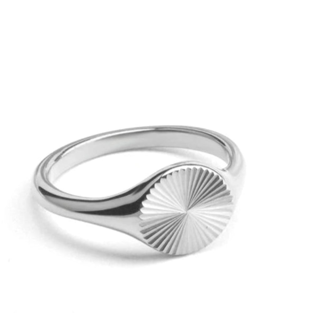 Silver ring with sunburst design on a circular face