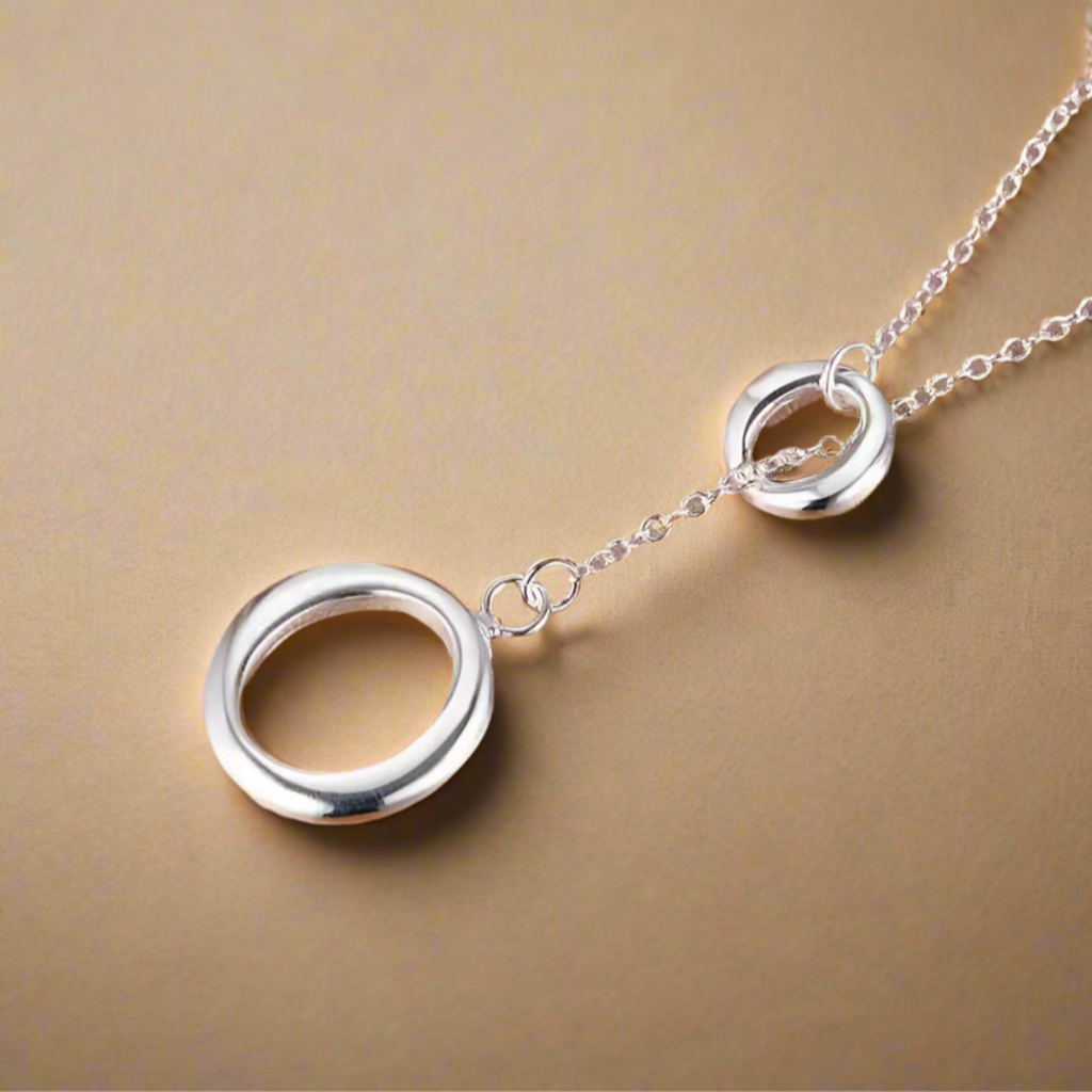Silver necklace with interlocking circles on a gold background.