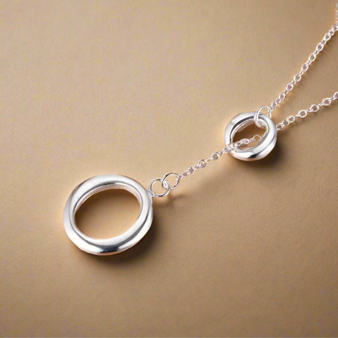 Silver necklace with interlocking circles on a gold background.