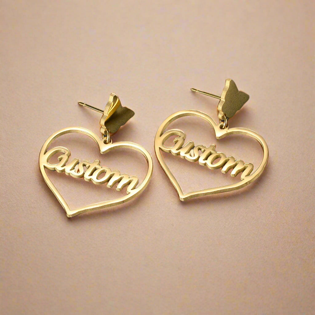 Custom gold heart-shaped earrings on a dark background.