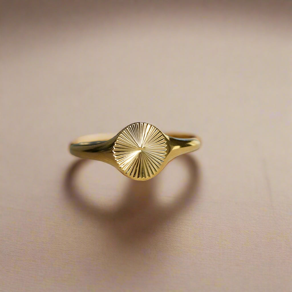Elegant gold ring featuring a sunburst etching.