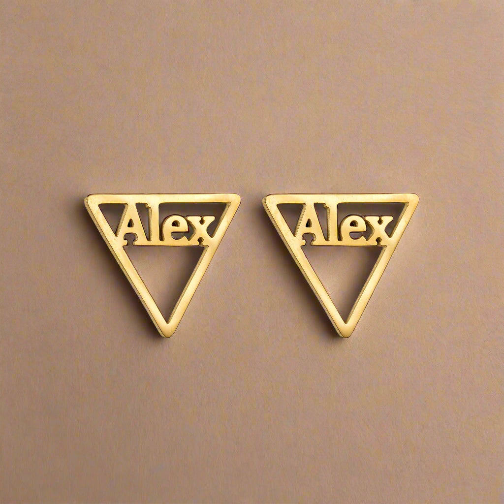 Gold triangle earrings with name “Alex” on black background.  