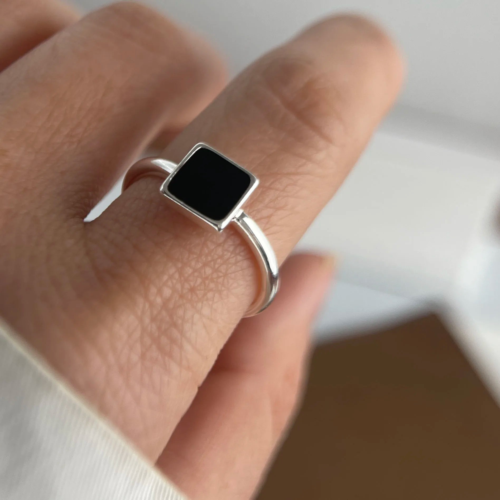 Adjustable black square silver ring worn on hand with casual outfit
