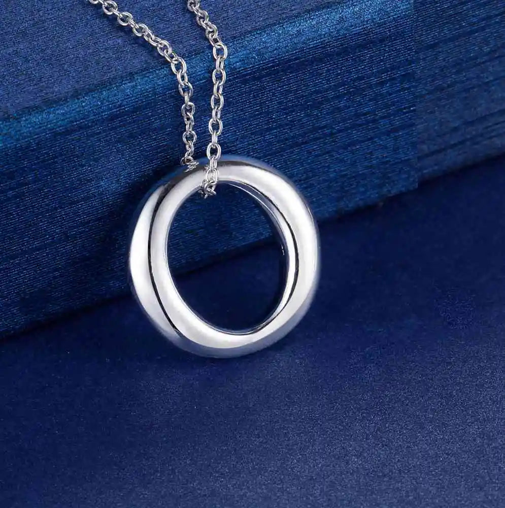 Circular silver pendant on blue textured background.  