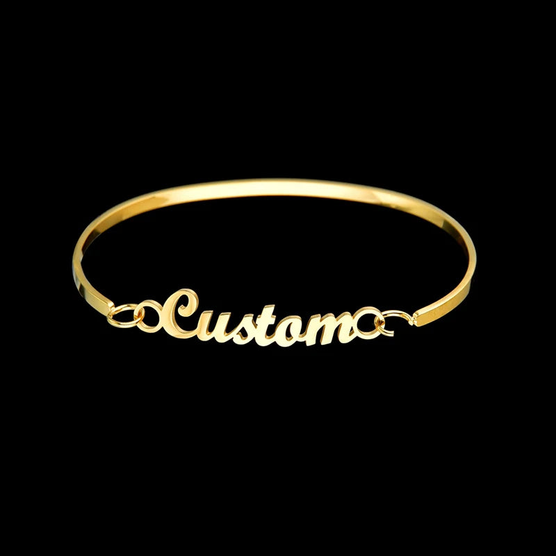 Gold bracelet with 'Custom' engraving on a black background