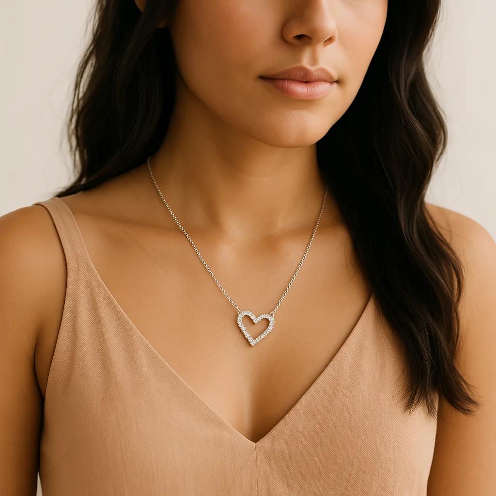 Woman wearing a silver heart-shaped necklace against a neutral background